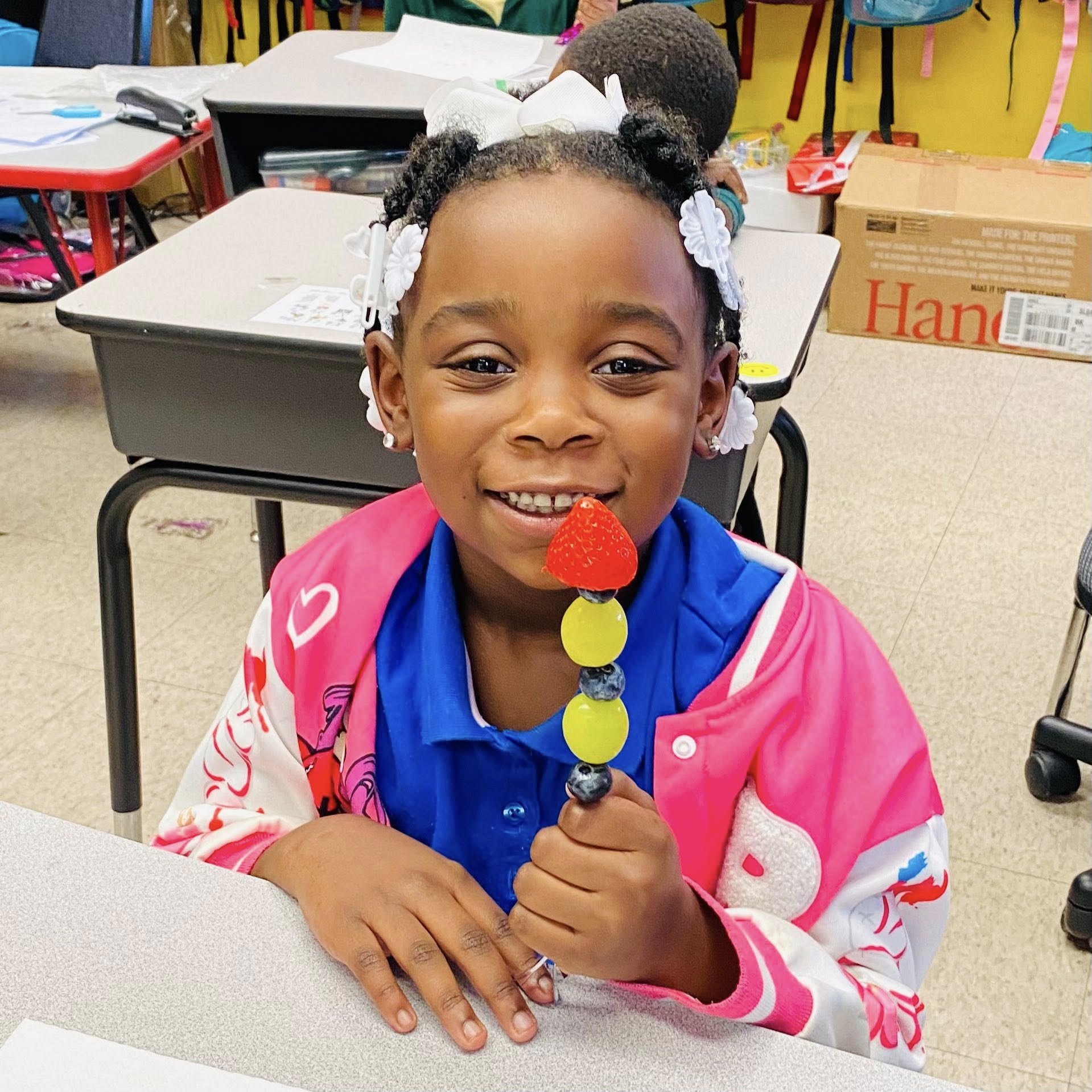 A girl holding a fruit kabob.